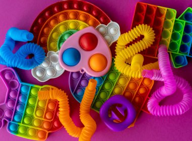 Stres önleyici oyuncaklar eğitim konsepti. Çocuklar arasında popüler bir oyuncak. Pembe arka plan. Patlat ve tüp oyununu patlat. Düz yatıyordu