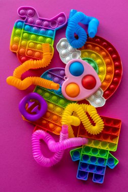 Stres önleyici oyuncaklar eğitim konsepti. Çocuklar arasında popüler bir oyuncak. Pembe arka plan. Patlat ve tüp oyununu patlat. Düz yatıyordu