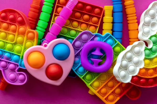 Stres önleyici oyuncaklar eğitim konsepti. Çocuklar arasında popüler bir oyuncak. Pembe arka plan. Patlat ve tüp oyununu patlat. Düz yatıyordu