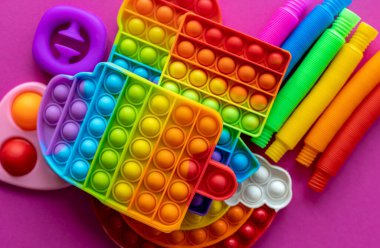 Stres önleyici oyuncaklar eğitim konsepti. Çocuklar arasında popüler bir oyuncak. Pembe arka plan. Patlat ve tüp oyununu patlat. Düz yatıyordu