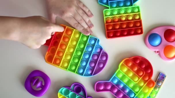 孩子们的手玩着小孩子们喜爱的彩虹玩具 白色背景 流行的抗压力游戏 平躺在床上 — 图库视频影像