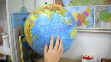 Çizgili sarı kazaklı kız parmağını Montessori okulundaki dünya gezegenini işaret ediyor. Dünyayı eğitim için kullanma kavramı coğrafya ve gezegenin yapısı.