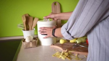 Adult woman peels potatoes with a vegetable peeler. People are vegetarian. Home kitchen interior. Zero waste concept. Conscious consumption of vegetables