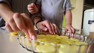 Erkek çocuk annesinin mutfakta duran sebzeli ratatouille 'i pişirmesine yardım ediyor. Aile gelenekleri. Evde Montessori eğitimi. Vejetaryen gıda konsepti.