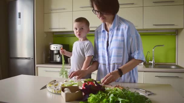 男の子の子供は彼のお母さんが台所に立つ野菜のラタトゥイユを調理するのを助ける 家族の伝統 家でのモンテッソーリ教育 ベジタリアンフードコンセプト — ストック動画