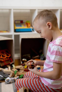 Children pull out wooden railway from a toy box. Educational toys for young children. Little boy wants to play construction set on the brown floor at home or in kindergarten.