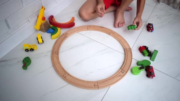 孩子们玩木制铁路 玩玩具火车的孩子可爱的孩子玩汽车和引擎 幼儿教育玩具 小男孩在家里或幼儿园的白色地板上建造铁路轨道 — 图库视频影像
