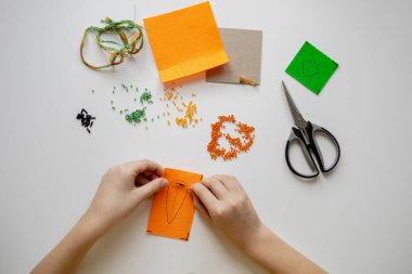 Child girl weaves a brooch from beads. Handmade. Favorite hobby. Diy process
