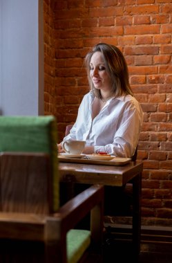 Kadın takım elbiseli bir kadın elinde bir telefon tutuyor ve pencereden dışarı bakıyor. Yemek molası. Ofis çalışanı.