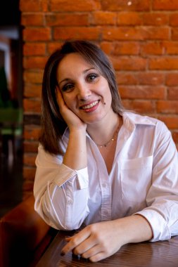 Genç kadın kanepedeki bir masada bir kafede oturuyor. Kahvaltıyı bekliyorum. Mola sırasında mahremiyet.