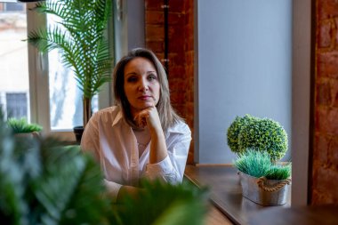 Kadın ofis çalışanı bir kafede oturuyor. Bir kadın portresi. Freelancer öğle yemeğini bekliyor.