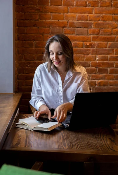 Masadaki Kafede Oturan Beyaz Gömlekli Genç Bir Kadın Dizüstü Bilgisayarda — Stok fotoğraf