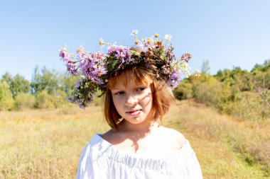 Kafasında çiçek çelengi olan bir kız. Doğada yürü. El yapımı dekorasyon. Sıcak bir gün. Ivan Kupala ziyafeti