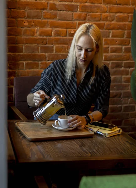 Çaydanlığı tutan ve beyaz fincana çay dolduran bir kadının eli. İş kadını mesaiden sonra hafif bir çay saati geçiriyor. Antioksidanlı yeşil bitki