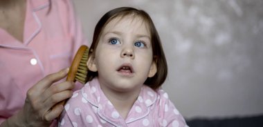 Anne sabahleyin yatağında otururken küçük kızının saçını tarar. İyi sabahlar. Mutlu aile kavramı. Boş zaman..