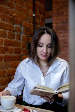 Genç bir kadın bir fincan kahveden içer. İş yemeği molası. Kafede geçirilen zaman