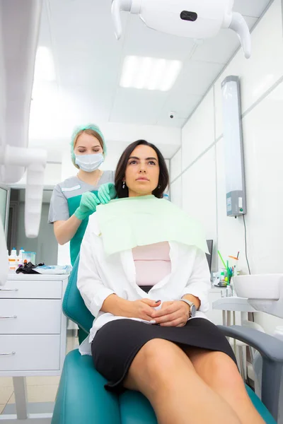 The dentists assistant puts the protection on the patient, the napkin on the chest — Stock Photo, Image