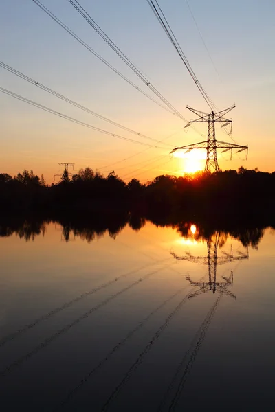 Pilone elettrico con riflessione in acqua al tramonto — Foto Stock