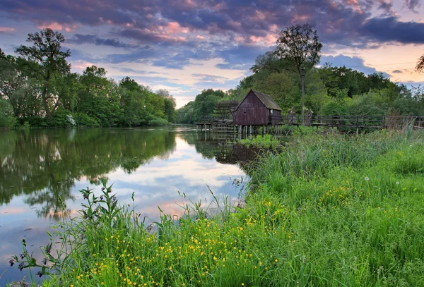 Jarní krajina při západu slunce s vodní mlýn a řeka — Stock fotografie