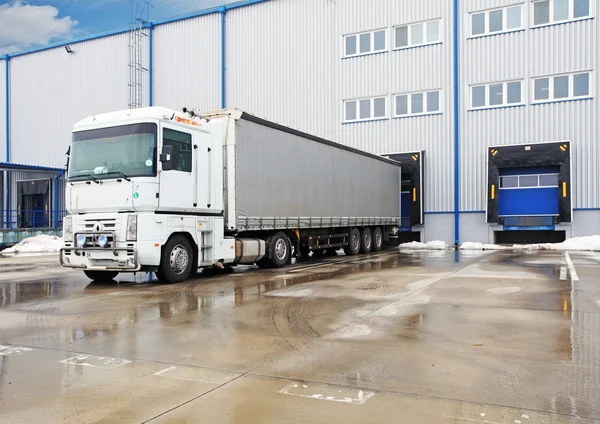 Entladen großer Containerlaster an Lagerhalle Stockbild