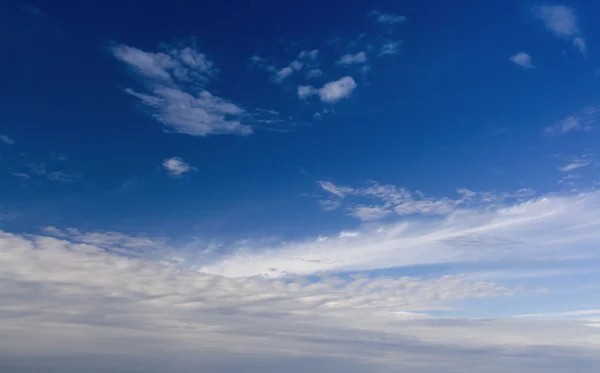 En djupblå himmel med fluffiga vita moln — Stockfoto