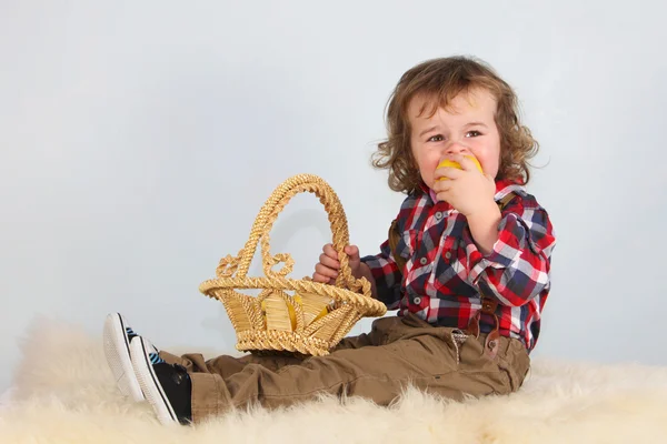 Liten gutt med kurv som spiser eple – stockfoto