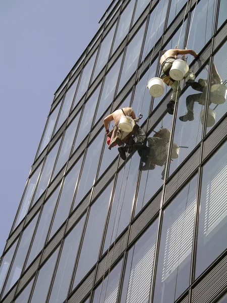 Un hombre limpiando ventanas en un edificio alto — Foto de Stock
