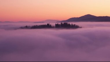 Bulutların üzerinde dağ, gün doğumunda zaman doluyor.