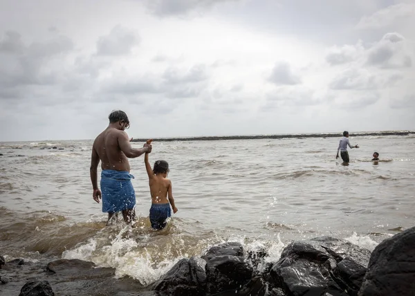 Mumbai,India-07-30-2022:people and children venturing dangerously in haji ali poluted sea waters during high tides risking their lives