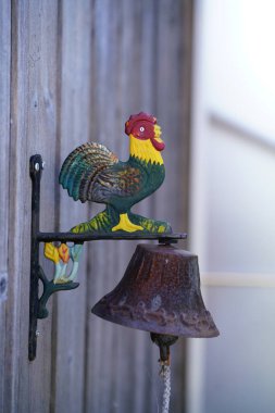 İsviçre 'de bir dağ evinin duvarında çan çalan horoz.