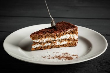 Beyaz tabakta bir parça çikolatalı kek. Siyah tahta arkaplan.