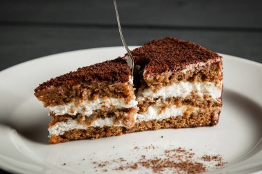 Beyaz tabakta bir parça çikolatalı kek. Siyah tahta arkaplan.