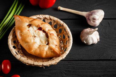 Pie in a wicker basket on a black wooden background.