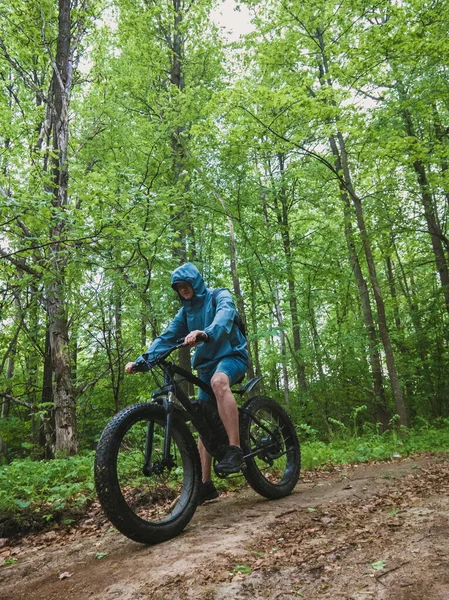 Yetişkin bir adam, toprak bir yolda elektrikli bir motosikletle dağdan aşağı iniyor. Doğada sağlıklı spor hobisi.