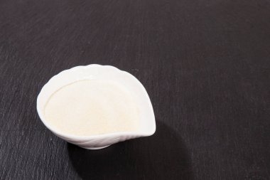 Kolajen tozu, siyah arkaplanda. Ek protein alımı. Cilt, kemik, eklem ve bağırsak için doğal güzellik ve sağlık desteği.