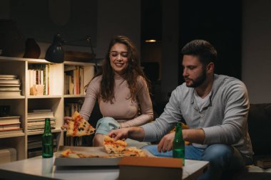 Arkadaşlar evde pizza yiyorlar.
