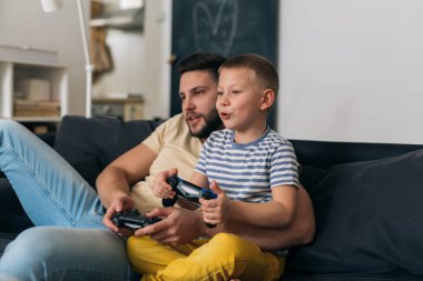 baba ve oğul evde video oyunu oynuyorlar.
