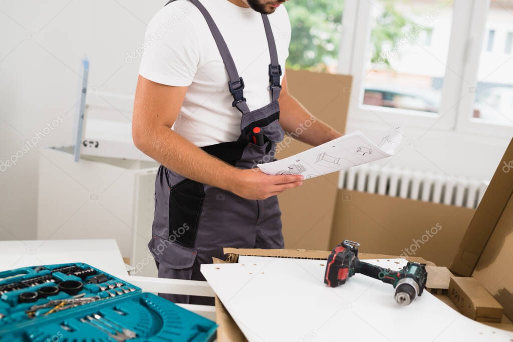 handyman reading user manual while assembling kitchen