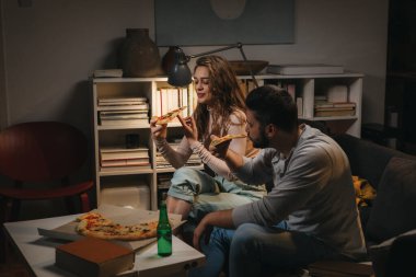 Arkadaşlar evde, pizza yiyor ve eğleniyorlar.