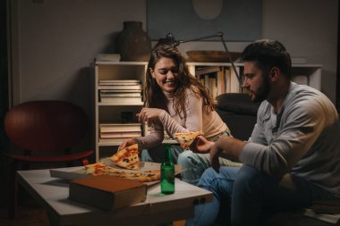 Arkadaşlar evde, pizza yiyor ve eğleniyorlar.