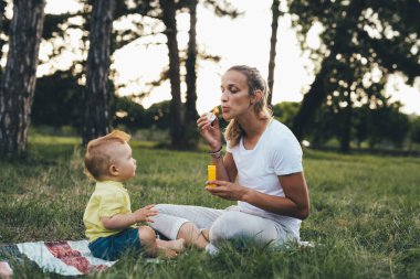 Anne ve oğlu halk parkında oynuyorlar.
