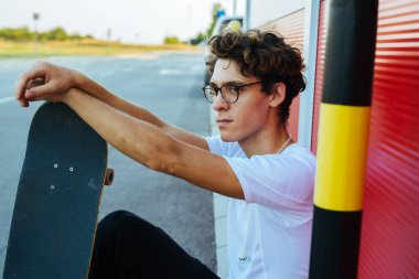 Kaykaycı kaykayla dışarıda poz veriyor.