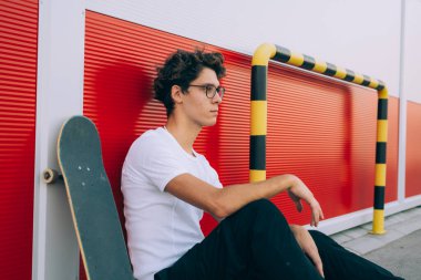 Kaykaycı kaykayla dışarıda poz veriyor.