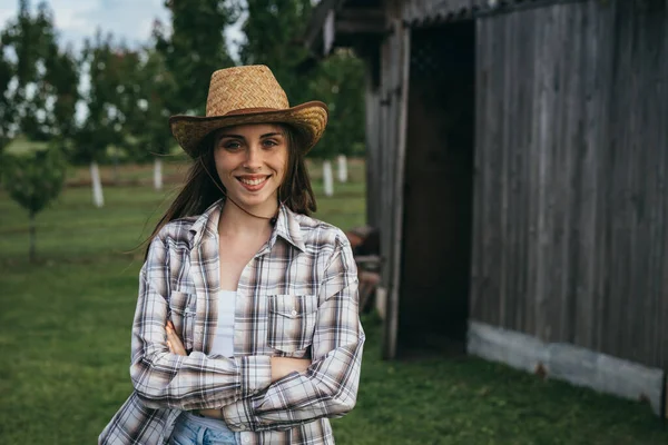 woman farmer posing outdoor in front of wooden barn