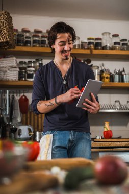 Adam mutfakta yemek yapmayı öğreniyor. dijital tablette tarifler aranıyor