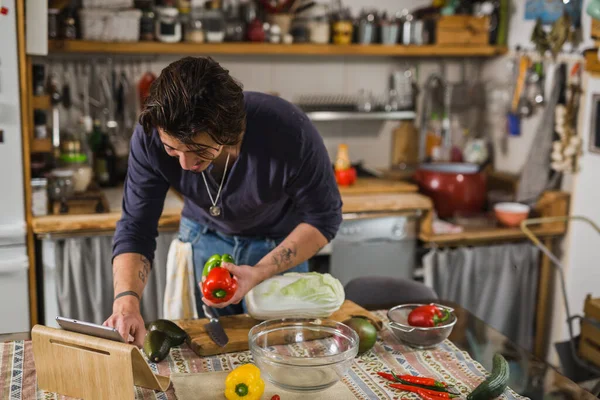 Adam mutfakta yemek yapmayı öğreniyor. dijital tablette tarifler aranıyor