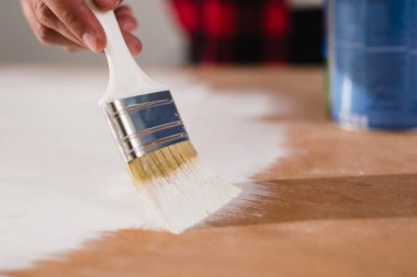 Adam eski kapıyı tamir ediyor. Beyaz boyayla resim yapıyor.