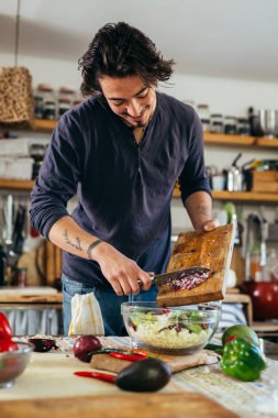 Adam mutfağında salata hazırlıyor.
