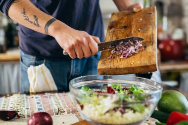 Adam salataya kırmızı soğan ekliyor. Yakın çekim.