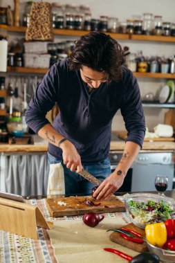 Adam mutfakta kırmızı soğan kesiyor.